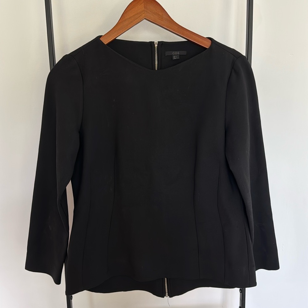 Black top by COS. Zipper in the back. Good condition